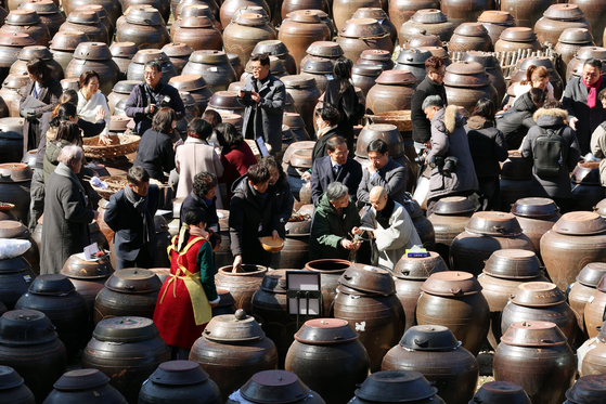People attempt to make jang, or fermented sauce, in Damyang County, South Jeolla, on Feb. 18 at an event celebrating the culinary tradition's addition to Unesco's Intangible Cultural Heritage list last December. Jang-making is Korea's 23rd entry on the Unesco list. [YONHAP]
