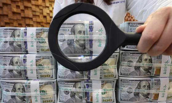A Hana Bank employee shows stacks of $100 bills at its forgery detection center in Jung District, central Seoul, on Feb. 18. [YONHAP]