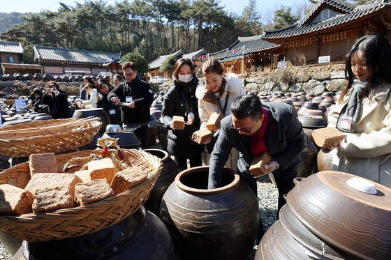 People attempt to make jang, or fermented sauce, in Damyang County, South Jeolla, on Feb. 18 at an event celebrating the culinary tradition's addition to Unesco's Intangible Cultural Heritage list last December. Jang-making is Korea's 23rd entry on the Unesco list. [YONHAP]