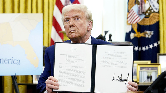 President Donald Trump holds up a signed executive order in the Oval Office of the White House on Feb. 13 in Washington. [AP/YONHAP]