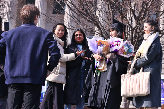 Students of Hankuk University of Foreign Studies take photos with friends at the school campus on Feb. 14. [YONHAP] 