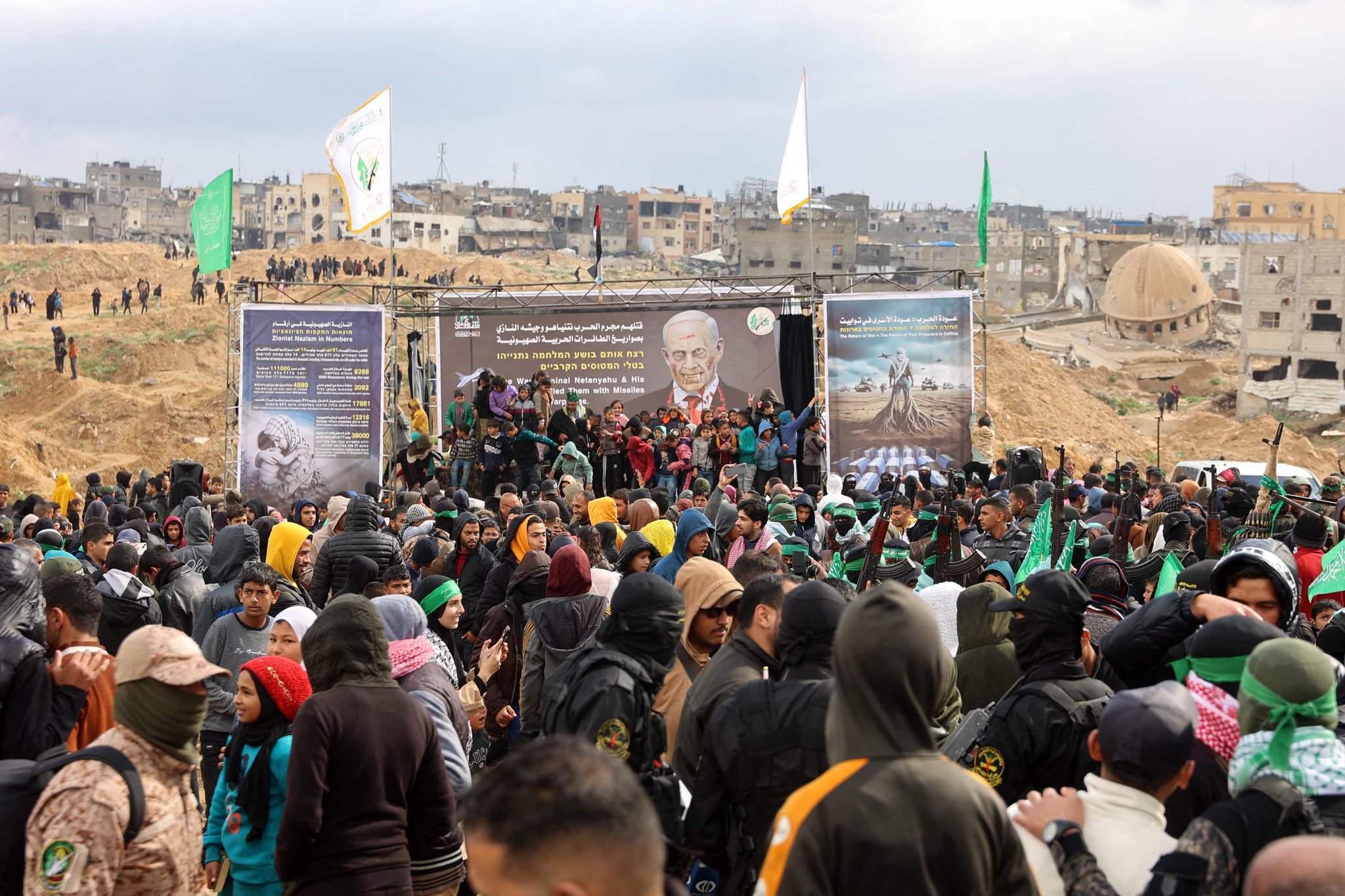 Palestinian Hamas fighters and people gather at the site of the handing over of the bodies of four Israeli hostages in Khan Yunis in the southern Gaza Strip on Feb. 20. [AFP/YONHAP]