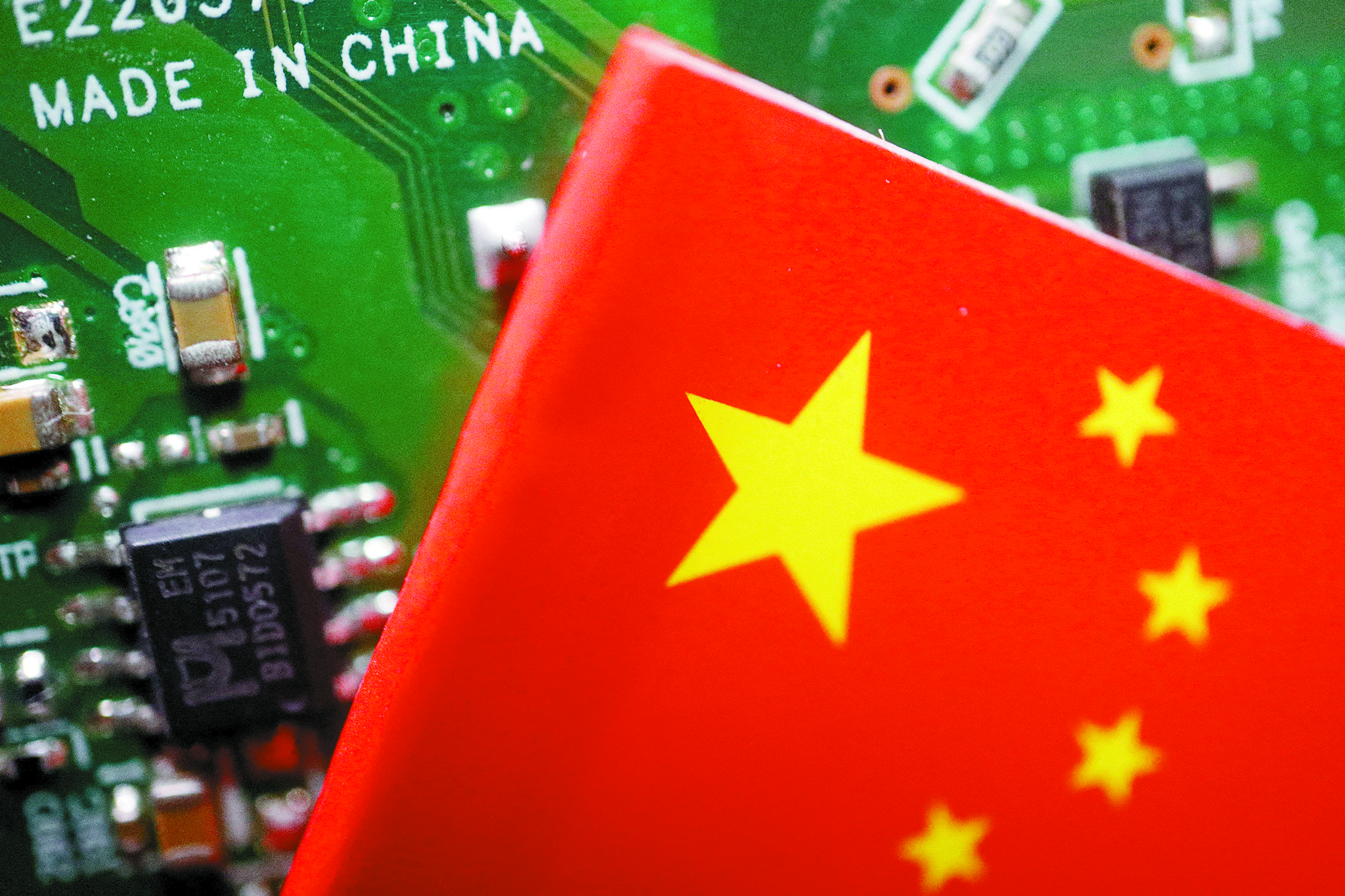 A Chinese flag is displayed next to a ″Made in China″ sign seen on a printed circuit board with semiconductor chips, in this illustration picture taken February 17, 2023. [REUTERS/YONHAP]