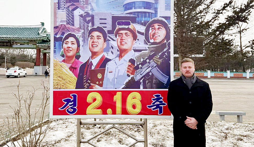 American independent filmmaker Justin Martell poses in front of a poster celebrating former North Korean leader Kim Jong-il's birthday inside the Rason special economic zone on Feb. 16. Martell told CNN he obtained a citizenship from Saint Kitts and Nevis to bypass the U.S. State Department's ban on travel to the North by its citizens. [SCREEN CAPTURE]