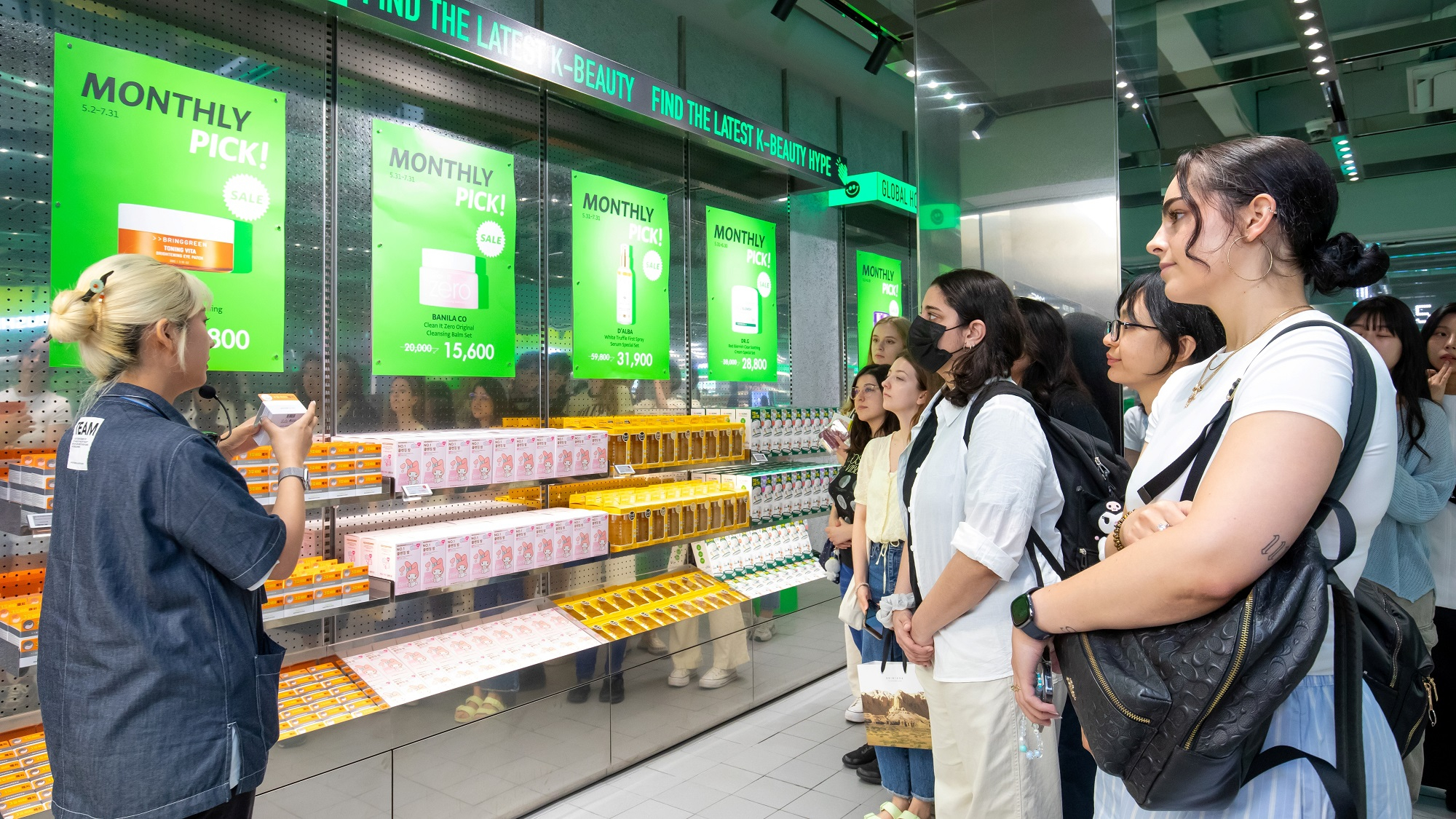 Olive Young staff explains a product to foreign customers at one of its branches. [OLIVE YOUNG]