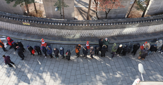 Older adults wait in line for lunch at a soup kitchen in Jongno District, central Seoul, on Feb. 3. [YONHAP]