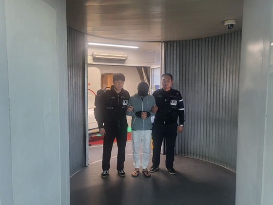 The ringleader of an investment fraud group, center, is being repatriated to Korea in this file photo provided by the Daegu Metropolitan Police Agency on Feb. 25. [DAEGU METROPOLITAN POLICE AGENCY]