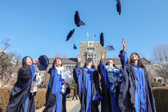 Students of Yonsei University throw their mortarboards in the air after their graduation ceremony on Monday. [NEWS1]