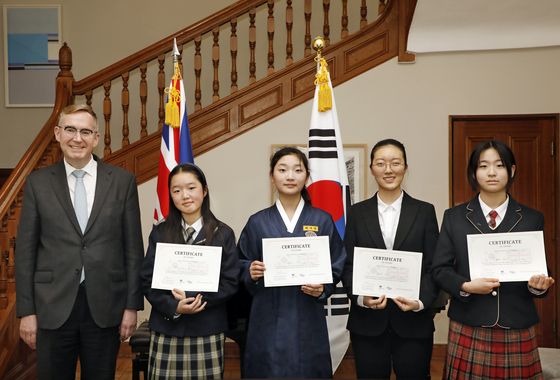 British Ambassador to Korea Colin Crooks, far left, and four junior female students who completed the British Embassy's ″Ambassador for a Day″ program pose for a photograph while holding their certificates at the ambassador's residence in Jung District, central Seoul, on Feb. 28. [PARK SANG-MOON]