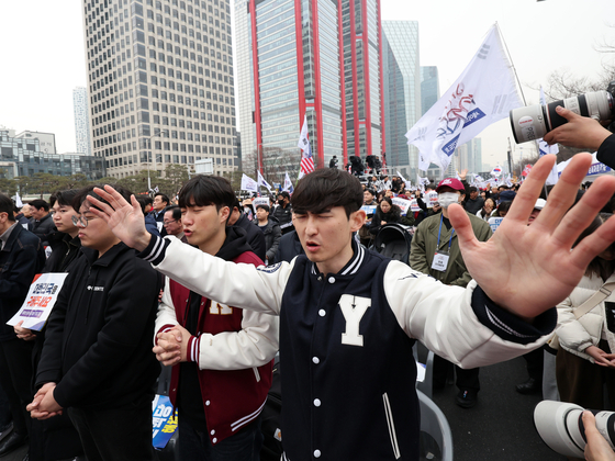 People wearing Yonsei University and Korea University varsity jackets pray at a rally against the impeachment of President Yoon Suk Yeol in Yeouido, western Seoul, on March. 1. [NEWS1]