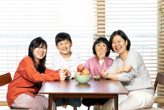Creators and models of the children's book ″If You Want to Eat a Red Apple″ (2024) pose for photos at photographer Lee Ga-hee's home in Incheon, last month. From left are Lee, her children Ji-gu and Ji-ho and writer Jin Joo. [JOONGANG ILBO]