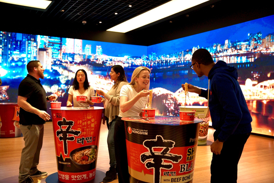 Customers enjoy Nongshim Shin Ramyun instant noodles at a promotional event in New York on Nov. 8, 2024. [YONHAP]
