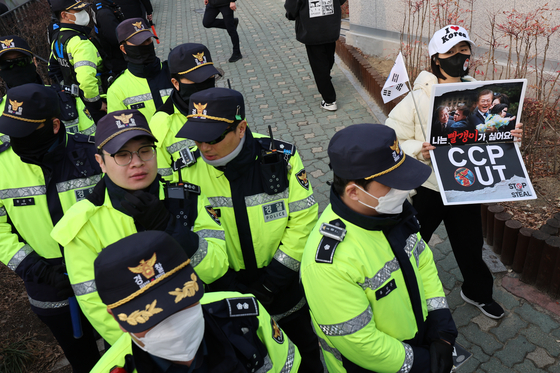 A protester against President Yoon Suk Yeol's impeachment passed by police holding her "anti-commie" picket on March 7 in front of the presidential residence at Yongsan District, central Seoul, as they hear the news of Yoon's arrest being overturned by the court. [NEWS1] 