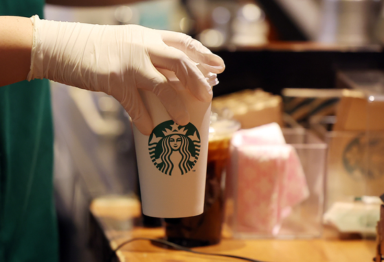 A barista hands a beverage to a customer at a Starbucks branch in Seoul on Jan. 24. Starbucks Korea raised prices for the tall size of 22 items on its menu, including the popular Americano, by 200 won (15 cents) on Jan. 24. [NEWS1] 