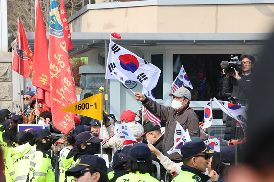 Protesters against President Yoon Suk Yeol's impeachment wave flags at the presidential residence at Seoul Detention Center in Gyeonggi on March 7 as they hear the news of Yoon's arrest being overturned by the court. [NEWS1] 