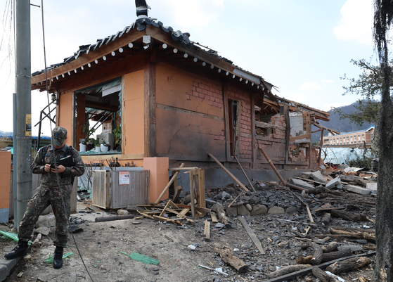 A person in military uniform is seen at a severely damaged home after eight bombs fell over Pocheon, Gyeonggi, during a Korean Air Force live-fire exercise on March 6. [YONHAP]
