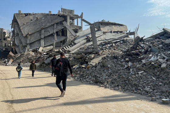 Palestinians walk past the rubble of destroyed houses, amid a ceasefire between Israel and Hamas, in Khan Younis in the southern Gaza Strip, on March 6. [REUTERS/YONHAP]