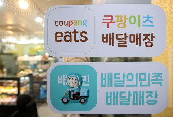 Coupang and Baedal Minjok stickers are on a restaurant in Seoul [NEWS1]