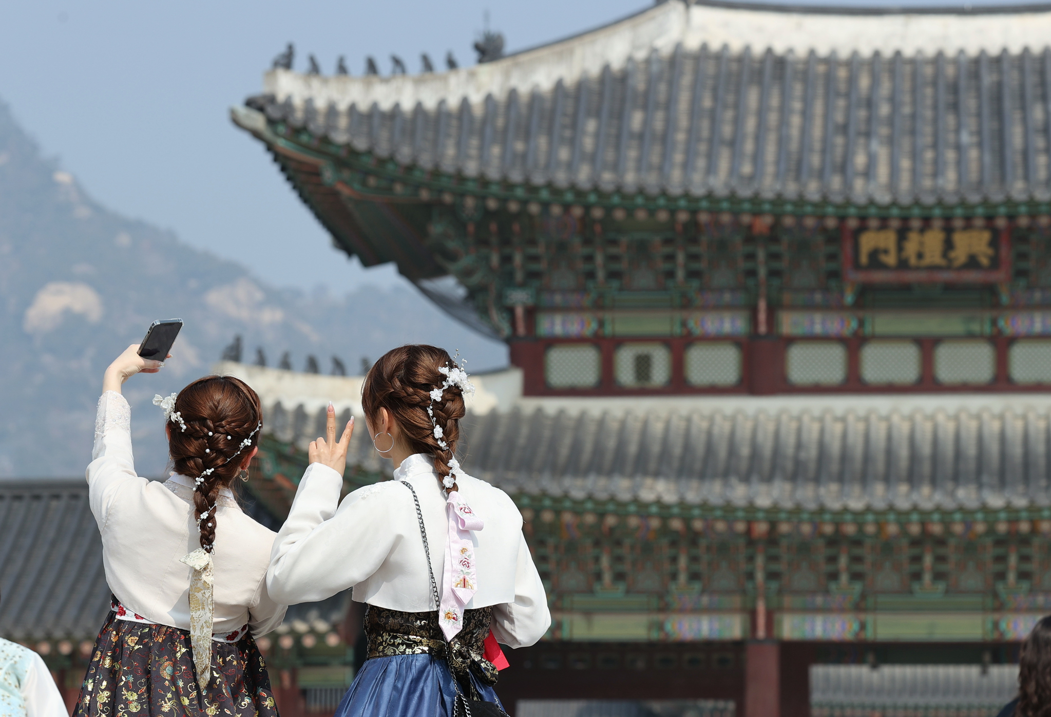 Visitors in hanbok, or traditional Korean dress, take selfies near Gyeongbok Palace in Jongno District, central Seoul, on March 10. [YONHAP]