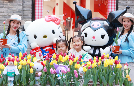 Children pose with Everland employees handing out tulips in Myeong-dong, central Seoul, on March 11 to promote the amusement park's annual Tulip Festival. [YONHAP]