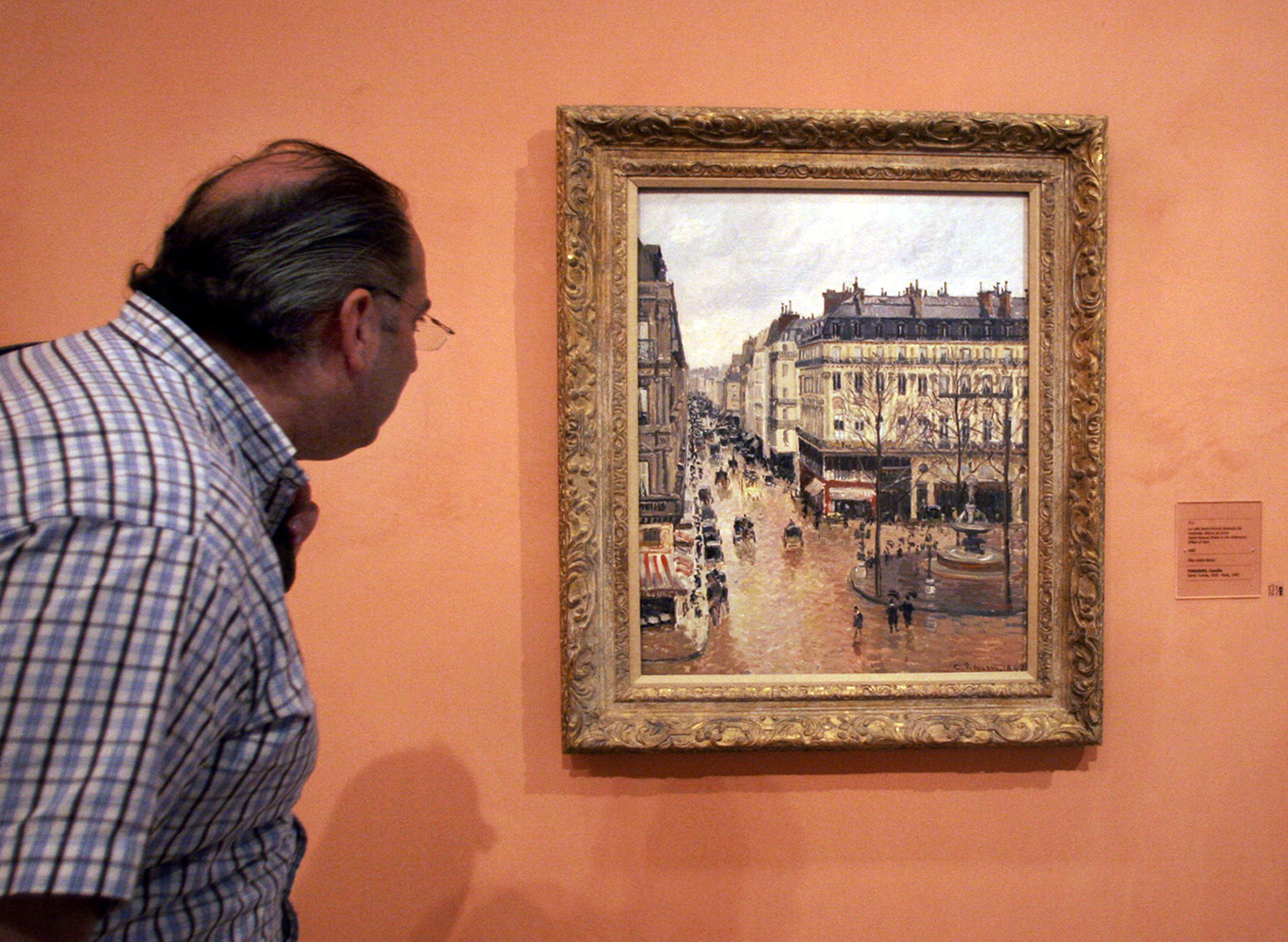 A visitor views the Impressionist painting called ″Rue St.-Honore, Apres-Midi, Effet de Pluie″ (Rue Saint-Honore in the Afternoon, Effect of Rain) painted in 1897 by Camille Pissarro, on display in the Thyssen-Bornemisza Museum May 12, 2005, in Madrid. [AP/YONHAP] 