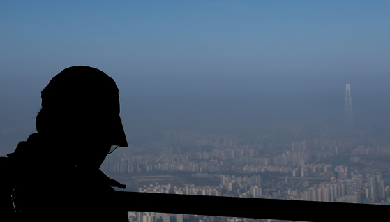 A person looks down into a hazy Seoul from the west gate of Namhansanseong Fortress on March 11. [YONHAP]