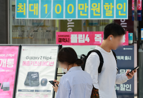Pedestrians pass by a mobile phone retailer in Seodaemun District, western Seoul, on Sept. 20, 2022. [YONHAP] 