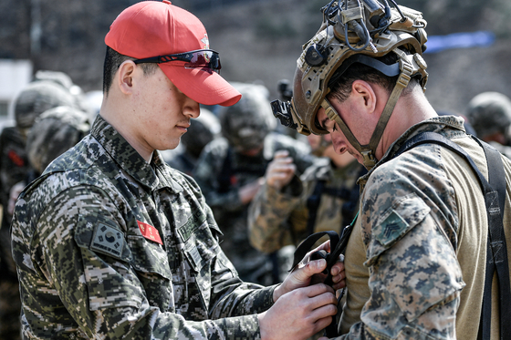 A South Korean marine checks a U.S. soldier's equipment before a rappel exercise in Gimpo, Gyeonggi, during joint drills with U.S. troops on March 12. [REPUBLIC OF KOREA MARINE CORPS]