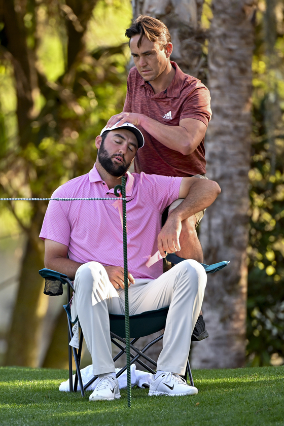 Scottie Scheffler, bottom, is looked for an injury before playing the 14th hole during the second round of The Players Championship at Stadium Course at TPC Sawgrass on March 15, 2024 in Ponte Vedra Beach, Florida. [GETTY IMAGES]