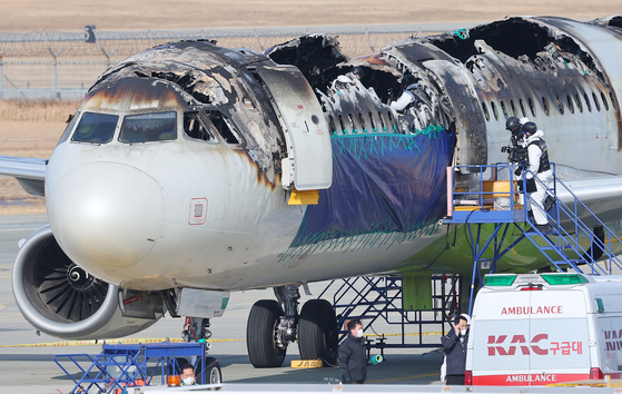 Officials from the Ministry of Land, Infrastructure and Transport's Aviation and Railway Accident Investigation Board inspect the burnt fuselage of the Airbus 321-200 operated by Air Busan at Gimhae International Airport in Busan on Feb. 3. [YONHAP] 