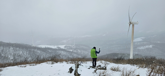 A visitor takes a photo of the snowy landscape in Pyeongchang County, Gangwon, on March 16, after a sudden cold snap brought snow and rain across the country. [YONHAP]