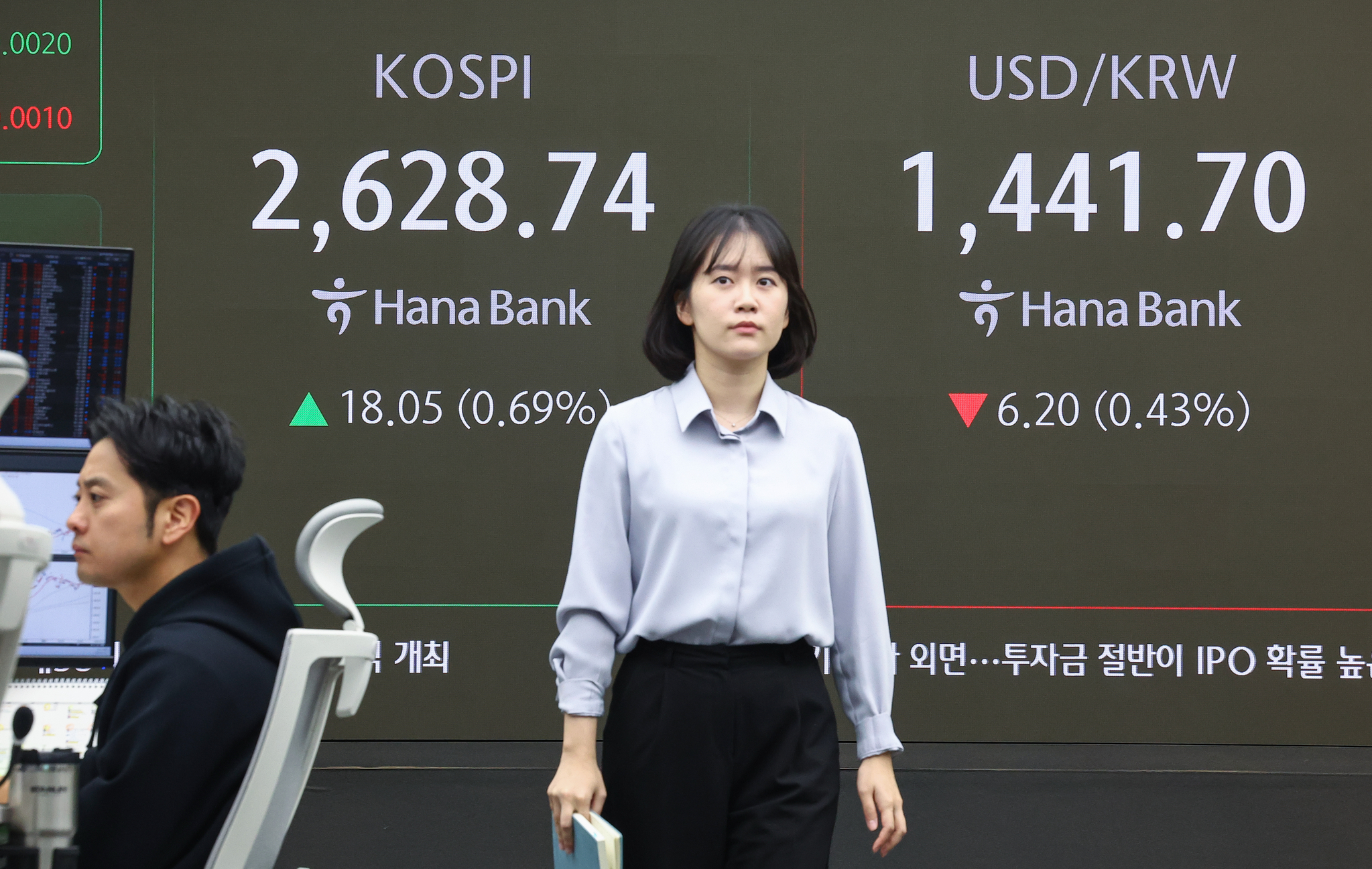 A person passes by a screen in Hana Bank's trading room in central Seoul on March 18. [YONHAP]