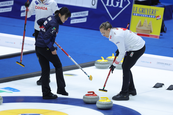 Korea's Gim Eun-ji, left, follows the stone during an LGT World Women's Curling Championship match against Canada at Uijeongbu Indoor Ice Rink in Uijeongbu, Gyeonggi on March 19. [YONHAP] 