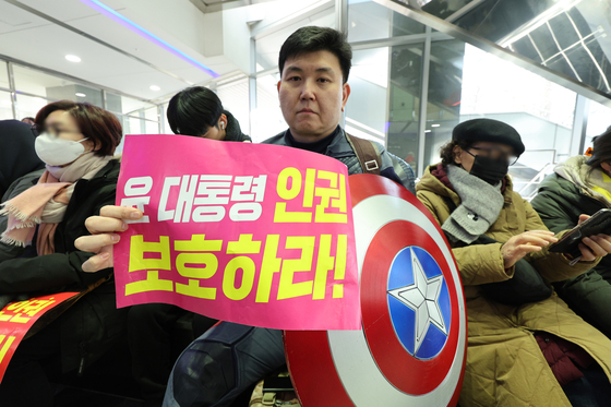 Ahn, holds up a placard saying ″Protect President Yoon Suk Yeol's human rights″ while wearing a costume of Captain America at the National Human Rights Commission of Korea's building on Feb. 10. [NEWS1] 