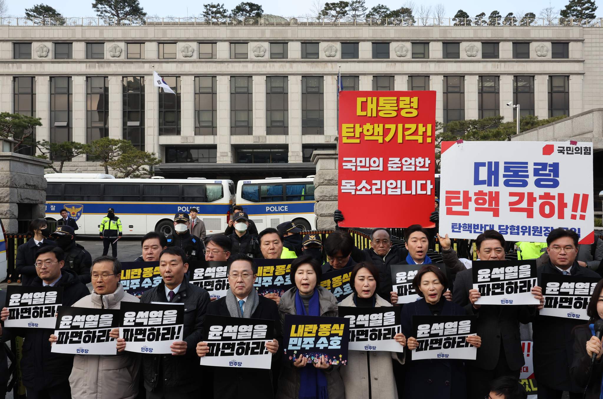 Lawmakers from the liberal Democratic Party hold up placards demanding President Yoon Suk Yeol's dismissal in front of the Constitutional Court in Jongno District, central Seoul, on March 20. They stand in front of posters calling on the court to reinstate the president. [YONHAP]