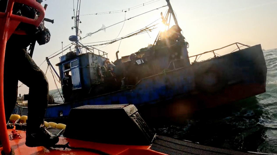 A Korea Coast Guard officer boards a Chinese fishing boat after seizing it for illegally fishing in waters near Socheong Island off Incheon on March 20. [KOREA COAST GUARD]