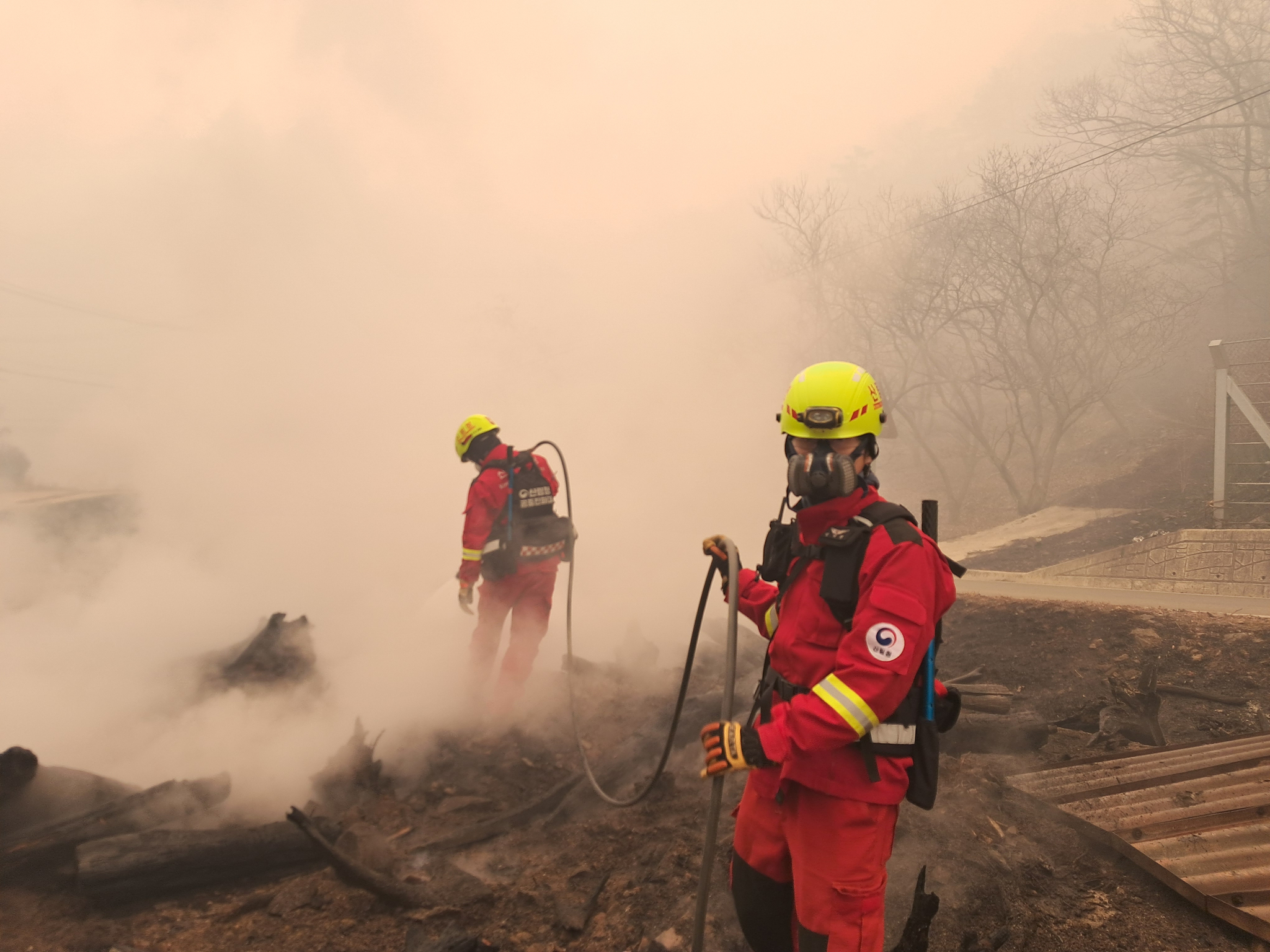 Two firefighters extinguish a blaze that erupted in Sancheong County in South Gyeongsang two days ago in a photo provided by the Korea Forest Service on March 23. [KOREA FOREST SERVICE] 