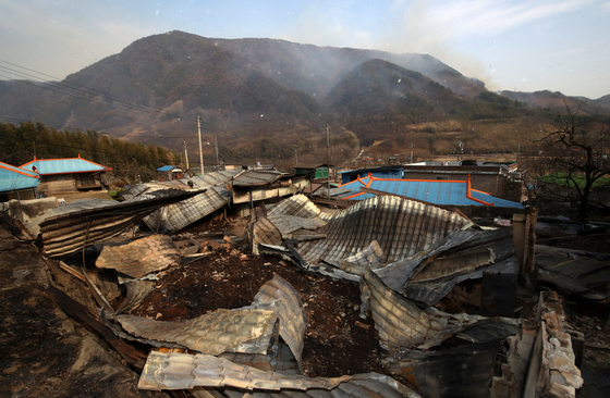 PIctured are destroyed residences in Sicheon-myeon, Sancheong County, South Gyeongsang as the wildfire rages on behind the neighborhood on March 23. [NEWS1] 