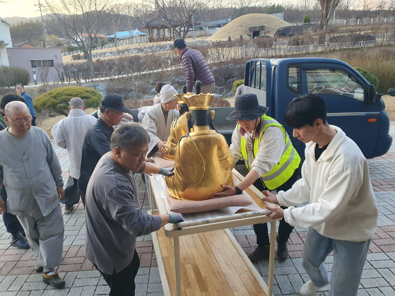 Monks and staffers transport golden Buddha statues to a safer area after a wooden temple was burned by a wildfire in Uiseong County in North Gyeongsang on March 22. [GOUN TEMPLE]