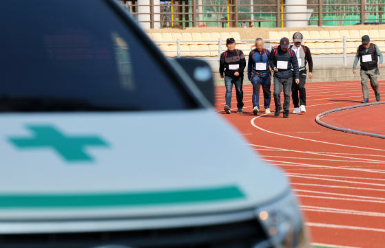 Applicants for a wildfire suppression team carry backpack pumps during a physical fitness test at Yellow City Stadium in Jangseong County, South Jeolla, on Jan. 23. [YONHAP]