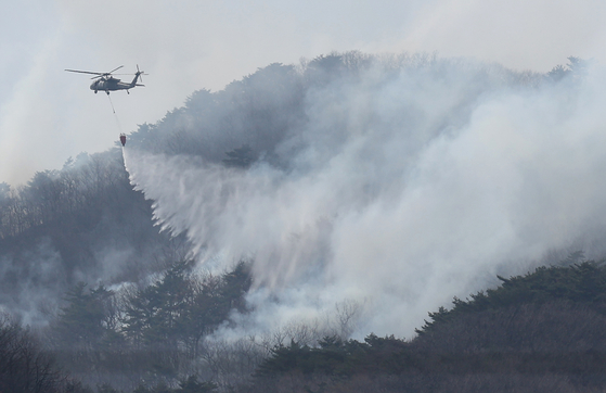 A helicopter joins firefighting efforts to suppress a wildfire in Uiseong County in North Gyeongsang on March 24. [YONHAP]