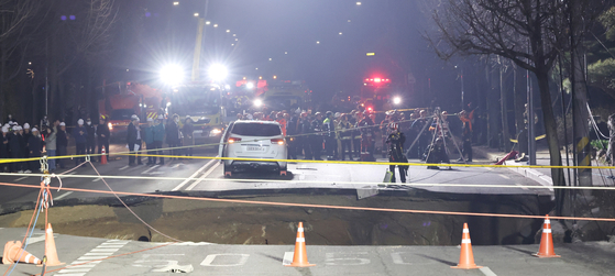 Emergency responders conduct a rescue operation at an intersection near Daemyung Elementary School in Gangdong District, eastern Seoul, after a sinkhole appears on March 24. [YONHAP]