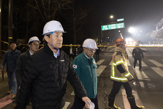 Seoul Mayor Oh Se-hoon, left, inspects the area near a 20-meter-wide sinkhole that appeared at an intersection in Gangdong District, eastern Seoul, on March 24. [NEWS1] 
