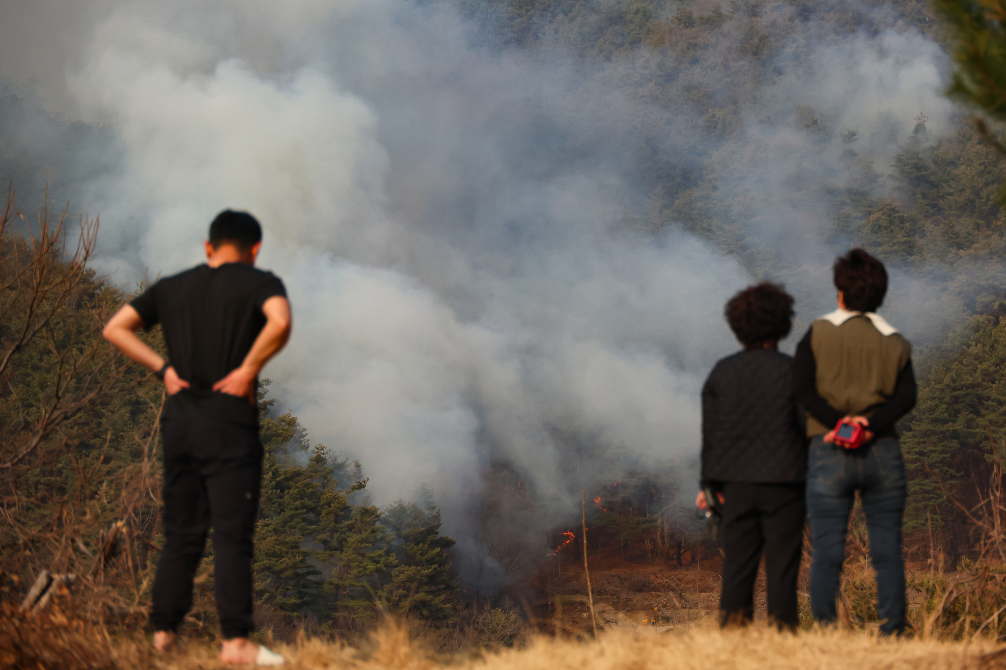 Residents in Sicheon-myeon, Sancheong County, South Gyeongsang look at a house blazed by the wildfire that has been sweeping the county on March 23. [YONHAP] 