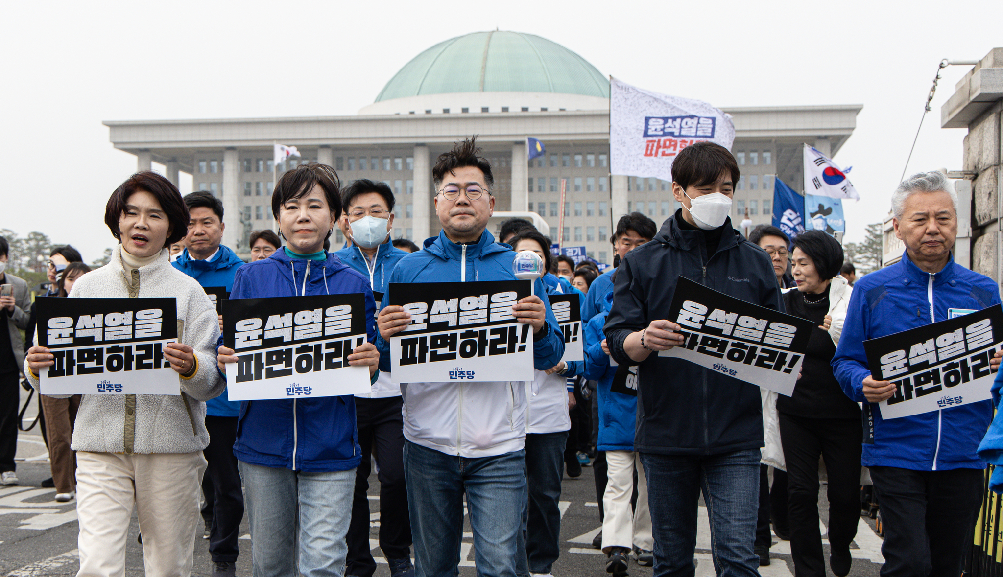 Democratic Party (DP) floor leader Rep. Park Chan-dae, center, and other DP lawmakers hold up placards urging the Constitutional Court to uphold President Yoon Suk Yeol's impeachment as they march in front of the National Assembly in Yeouido, western Seoul, on March 25. [NEWS1]