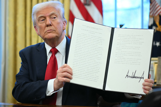 U.S. President Donald Trump displays an executive order he signed announcing tariffs on auto imports in the Oval Office of the White House in Washington on March 26. [AFP/YONHAP]