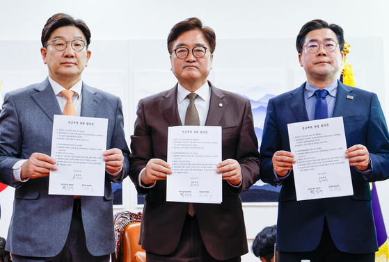 Conservative People Power Party floor leader Kweon Seong-dong, left, National Assembly Speaker Woo Won-shik, center, and liberal Democratic Party floor leader Park Chan-dae hold documents listing agreed provisions for the national pension scheme at the National Assembly in western Seoul on March 20. [NEWS1] 