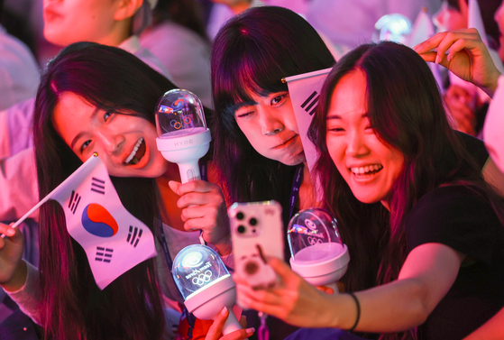 Olympic supporters take selfies with a lightstick made by HYBE and the Korean national flag Taegukgi on July 28, 2024, in Paris, France. [NEWS1]