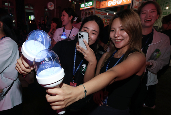 Olympic supporters take selfies with a lightstick made by HYBE on July 27, 2024, in Paris, France. [JOINT PRESS CORPS]