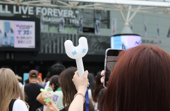 Fans take pictures of the K-pop goods of girl group NewJeans before a meet and greet event held on June 27 at the Tokyo Dome in Japan. [YONHAP]